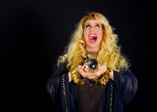 Laughing woman fortune teller with crystal ball portrait on black