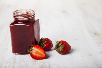 Jar of strawberry jam and ripe strawberries