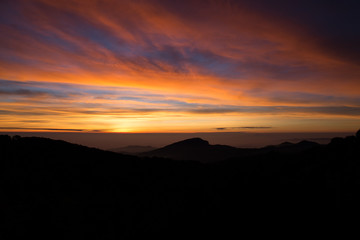 Morning mist in the mountains, bright blue sky, clouds in the foreground.