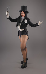 Obraz na płótnie Canvas Female magician in costume suit with magic stick doing trick