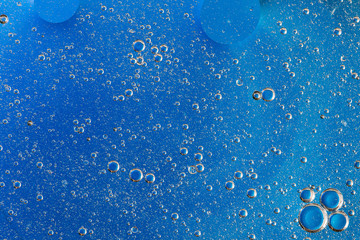 colorful oil bubbles on a water surface abstract background with blue