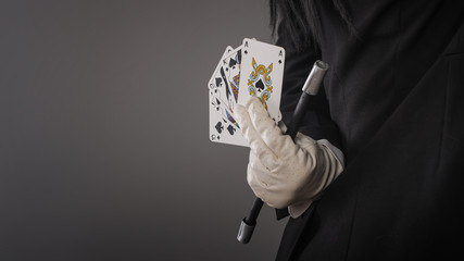 Magic wand and cards in hands of female magician. Closeup