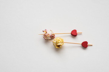 Still-life of festive multicolored popcorn on Valentine's day with colorful popcorn and two red hearts on white background