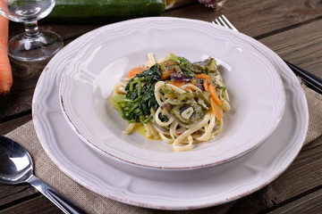 Plate of vegetarian pasta with carrot and zuccini spinach