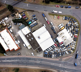 Aerial view of an industrial estate with many parking cars between two roads at the edge of a city