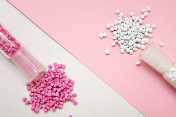 Obraz na płótnie Canvas Plastic pellets. Pink and white Colorant for plastics on a geometric background. Plastic Raw material .