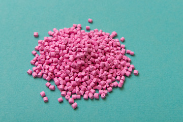 Plastic pellets. Pink Plastic granules on a turquoise background. Plastic Raw material .