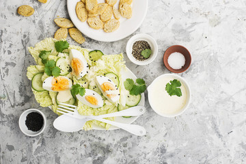 Curried egg' garden salad with lettuce, fresh cucumber slices, yogurt-based curry sauce, organic eggs with black sesame and green herbs. Top View.