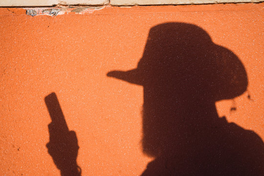 Male shadow with gun on wall