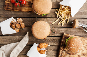 Wooden table with different fast food: burgers, nuggets, chicken balls, french fries - 187334697