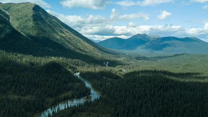 True wilderness. There is a river running through a remote Canadian forest, A cloudy but sunny day shows this untouched and uninhabited land. Very isolated from any sort of civilization.