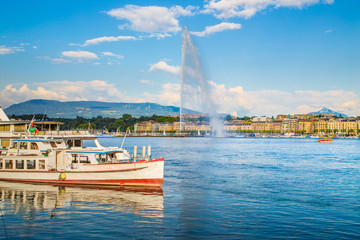 Geneva skyline with famous Jet d'Eau fountain and boat at sunset, Switzerland
