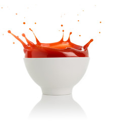 tomato soup splashing out of a bowl isolated on white