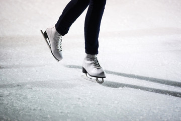 Young woman ice skating outdoors on a ice rink on a freezing winter day - detail of the legs