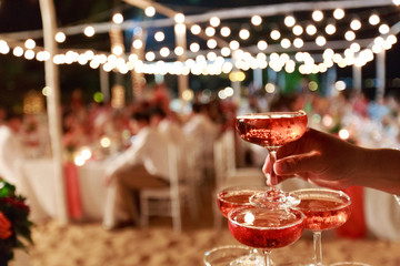 Pyramid from glasses of red wine on wedding party. Close-up of the pink champagne or wine pyramid in ceremony party.