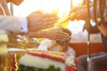 Water being poured on hands of the bride during a traditional Thai wedding ceremony. Hands pouring blessing water to the bride during a traditional Thai wedding ceremony.