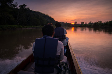 Fototapeta premium Man in a boat on a river at sunset.