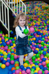 Fototapeta na wymiar Four-year girl playing with balls in the mall