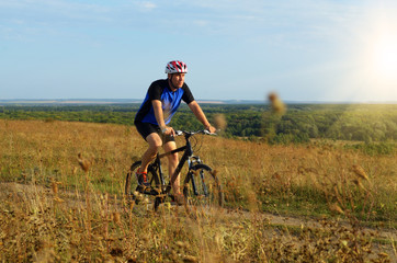 Fototapeta premium Male cyclist driving by rural dirt road outdoors