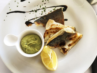 Sea Bass With Avocado Sauce And Slice Of Lemon.