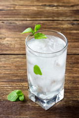 Refreshing beverage with mint and ice in a glass on a wooden table.