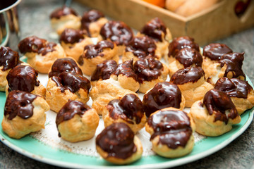 Chocolate covered vanilla cream pastry puffs close up.