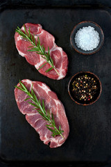 Fototapeta na wymiar Raw meat, pork steak on dark background, top view