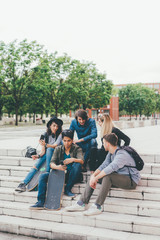 Obraz premium Group of friends multiethnic sitting outdoor using smart phone - technology, phubbing, internet concept