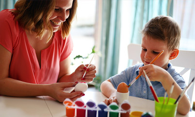 Happy young mother and son are painting Easter eggs