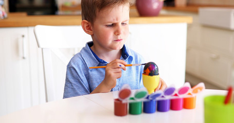Cute little boy painting easter eggs