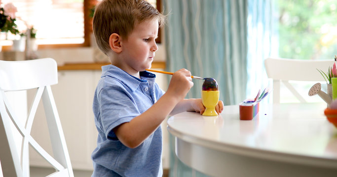 Cute little boy painting easter eggs