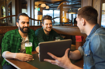 friends with tablet pc and green beer at pub