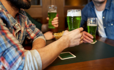 male friends drinking green beer at bar or pub