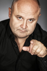 A bald man points with his finger