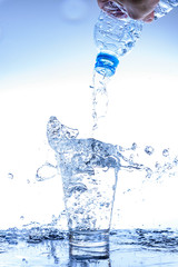 Pouring water and splashing in the glass with reflection on mirror.