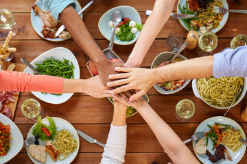 people holding hands together over table with food