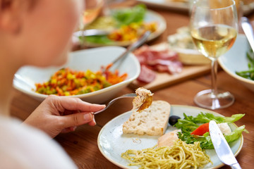 hands of woman eating pasta with chicken