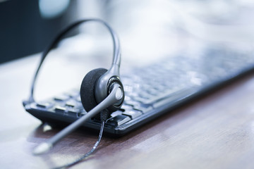 close up soft focus on headphone of call center with telephone devices at office desk for customer service support concept