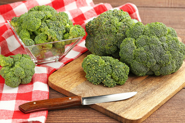 Fresh broccoli on brown cutting board with knife and red napkin