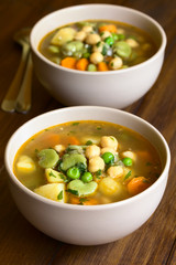 Vegetarian chickpea soup with carrot, broad bean (fava bean), pea, potato, onion, garlic, parsley, photographed with natural light (Selective Focus in the middle of first soup)