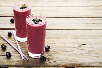 Blackberries yogurt in glasses on grey wooden table