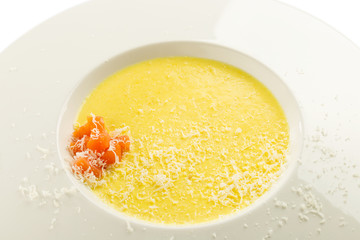 Cheese cream soup with salmon and grated parmesan on white plate isolated on white