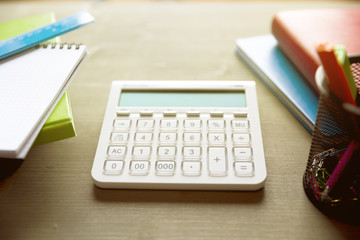 School and office supplies on wooden table with calculator in the middle