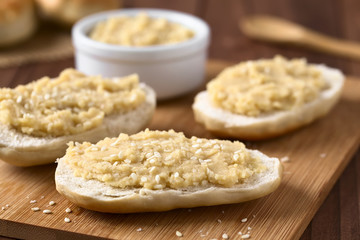 Chickpea spread or hummus on bread sprinkled with sesame seeds, photographed with natural light (Selective Focus, Focus on the middle of the first bread)