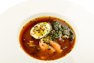 Thai soup with salmon, egg and seaweed on white background