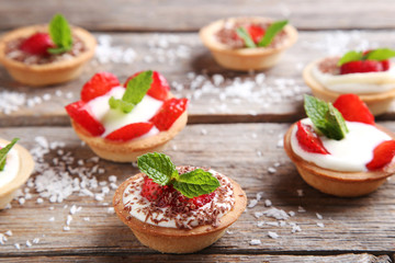 Fototapeta na wymiar Dessert tartlets with strawberries on grey wooden table