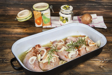 Raw chicken thighs in the pan with onions