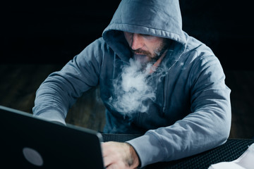 mysterious bearded man hacker smoking a hookah in the dark, hacking laptop