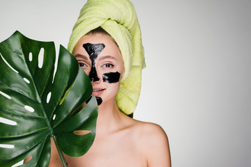 a cute young girl with a green towel on her head applied a black cleansing mask to the problem...