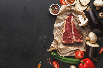 Raw t-bone steak on craft papper on dark background